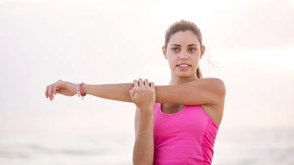 Woman doing a cross-body arm stretch outdoors